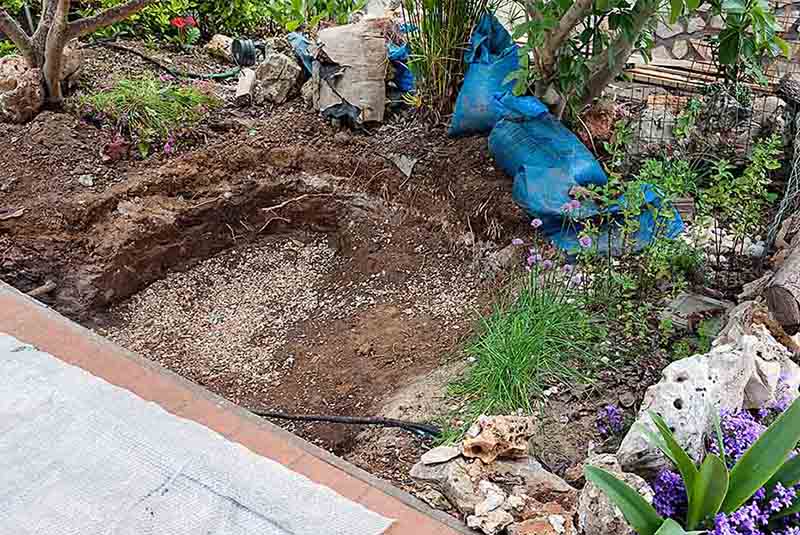 Hole excavated in the garden for artificial pond construction.